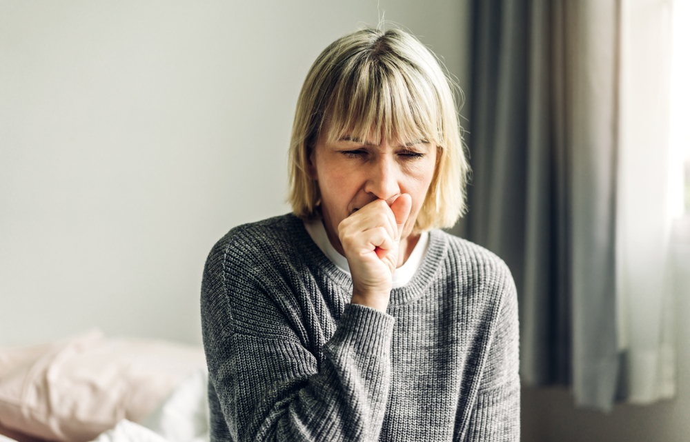 woman coughing into her fist.