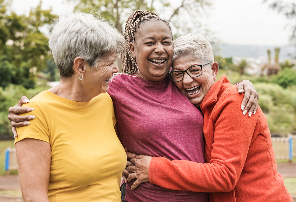 Three women laughing and hugging.