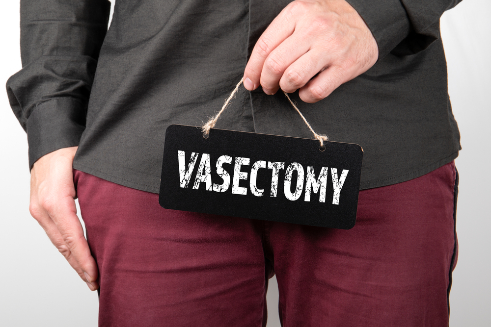 man holding little chalkboard with the word vasectomy written.